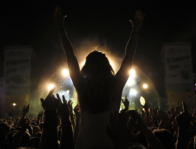 A girl sitting on shoulders in crowd with arms raised at Benicassim Music Festival in Spain