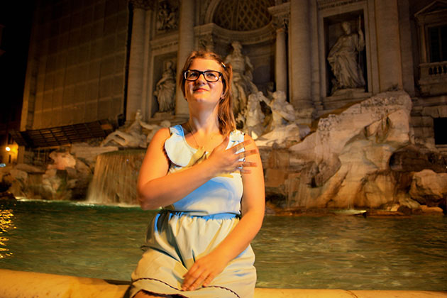 Trudy throwing a coin over her shoulder into the Trevi Fountain.
