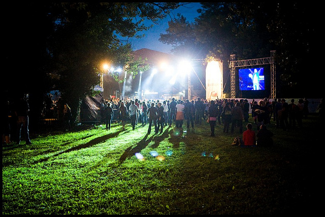 Crowd walking across grass at night towards a stage at INMusic Festival in Croatia.